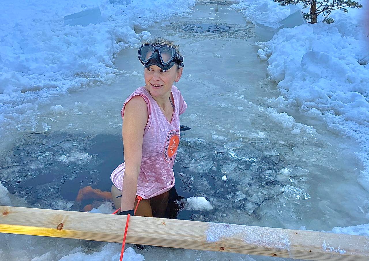 Mains agrippant le rebord en bois d'un bain de glace dans une forêt enneigée