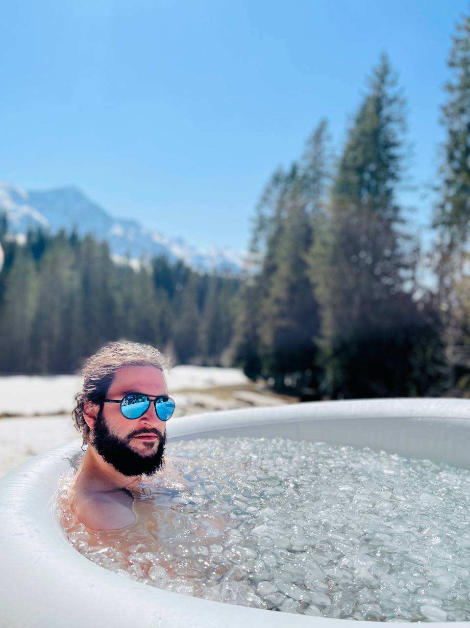 Participant portant des lunettes de soleil dans un bain de glace en pleine nature